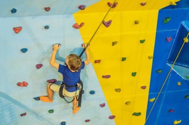 6 yaşında bir çocuk tırmanma merkezinde duvara tırmanıyor.