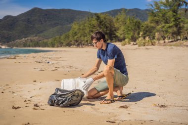 Eldivenli adam denizi kirleten plastik torbalar alıyor. İnsan yapımı kirlilik ve çevresel kirliliğin yol açtığı kumsala çöp dökme sorunu, konsept olarak gönüllü temizleme kampanyası