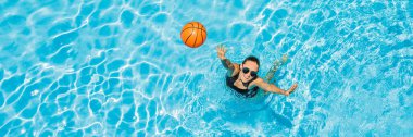 Genç bir kadın plaj topuyla havuzda oynuyor. BANNER, LONG FORMAT