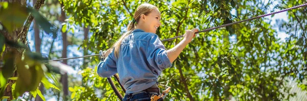 Jeune femme séduisante dans le parc de corde d'aventure dans l'équipement de sécurité BANNER, LONG FORMAT — Photo