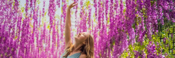 Schöne junge Frau zwischen rosa Blumen, die nach unten hängen BANNER, LONG FORMAT — Stockfoto