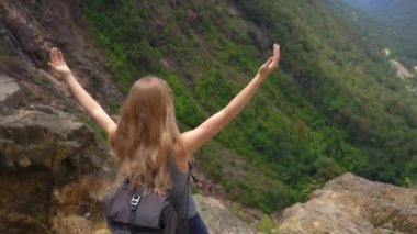 Dağlarda sırt çantalı genç bir bayan gezgin. Aşağıdaki görkemli vadiye bakıyor. Seyahat kavramı