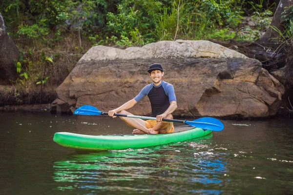 Vreugdevolle man traint SUP board in de rivier op een zonnige ochtend. Stand up paddle boarding - geweldige actieve outdoor recreatie — Stockfoto