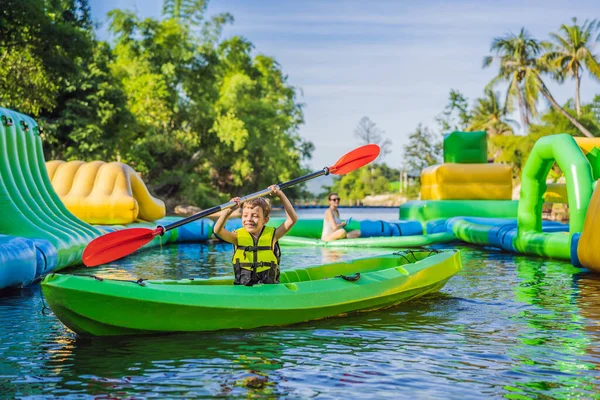 Anak laki-laki yang bahagia memegang dayung di kayak di sungai, menikmati hari musim panas yang indah — Stok Foto
