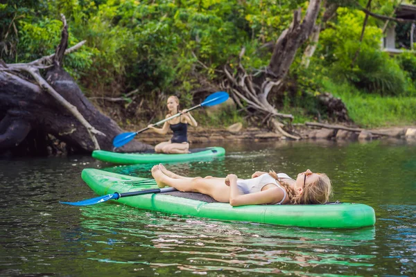 Zijaanzicht foto van een vrouw zitten en ontspannen op het sup board. Surfvrouw rustend — Stockfoto