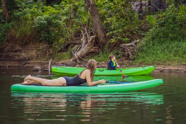 Foto vista laterale di una donna seduta e rilassante sulla tavola da sup. Surfer donna riposo — Foto Stock