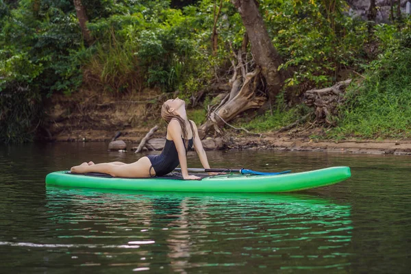 Sportliche Frau in Yogaposition auf dem Paddleboard, Yoga auf dem Sup Board, Bewegung für Beweglichkeit und Dehnung der Muskeln — Stockfoto