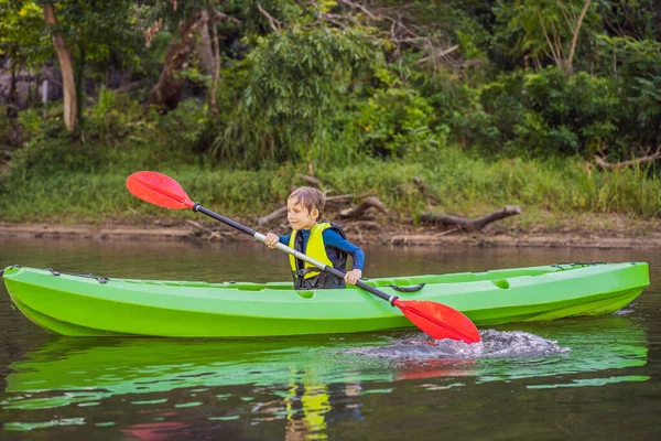 Glücklicher kleiner Junge mit Paddel im Kajak auf dem Fluss und genießt einen schönen Sommertag — Stockfoto