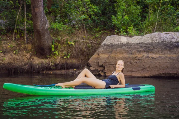 Vue latérale d'une femme assise et relaxante sur la planche à soup. Femme de surf au repos — Photo