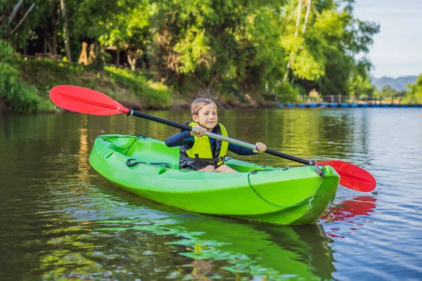 Gelukkig jong jongetje houden peddel in een kajak op de rivier, genieten van een heerlijke zomerdag — Stockfoto