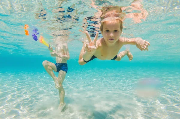 Nette Jungen schwimmen unter Wasser im seichten türkisfarbenen Wasser am tropischen Strand — Stockfoto