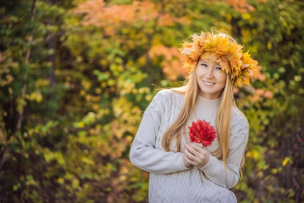 Estilo de vida ao ar livre close up retrato de encantadora jovem loira vestindo uma coroa de folhas de outono. Sorrindo, caminhando no parque de outono. Vestindo pulôver de malha elegante. Grinalda de folhas de bordo — Fotografia de Stock