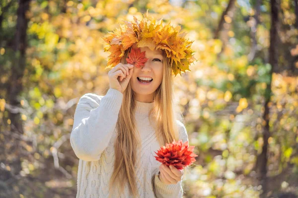 Stile di vita all'aperto primo piano ritratto di affascinante bionda giovane donna che indossa una corona di foglie autunnali. Sorridente, passeggiando nel parco autunnale. Indossa un pullover elegante a maglia. Ghirlanda di foglie d'acero — Foto Stock