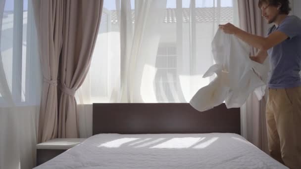 Een jongeman wisselt van bed op het bed — Stockvideo