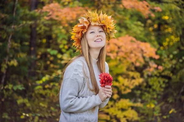 Draußen Lifestyle Nahaufnahme Porträt der charmanten blonden jungen Frau trägt einen Kranz aus Herbstblättern. Lächelnd spazieren wir durch den herbstlichen Park. Trägt stylische Strickpullover. Kranz aus Ahornblättern — Stockfoto