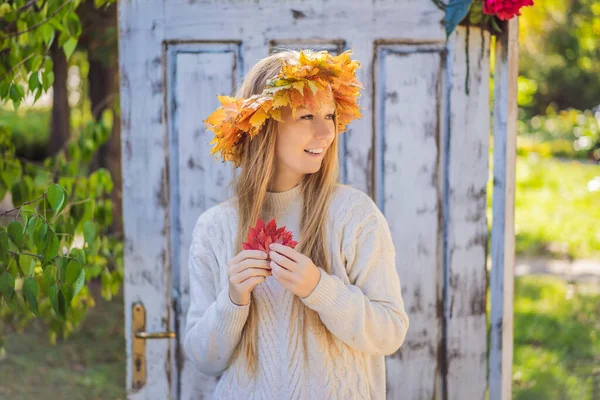Estilo de vida ao ar livre close up retrato de encantadora jovem loira vestindo uma coroa de folhas de outono. Vestindo pulôver de malha elegante. Grinalda de folhas de bordo — Fotografia de Stock