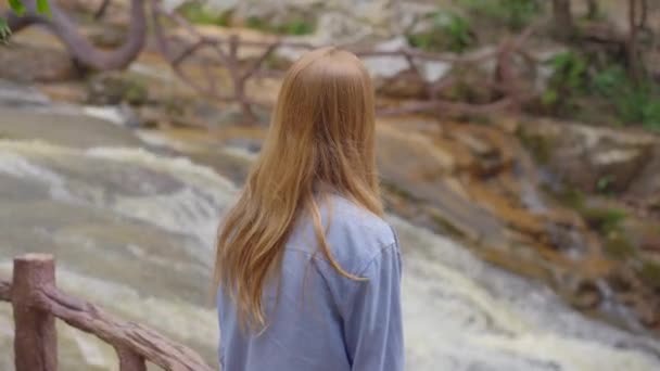 Una giovane donna visita una cascata in montagna. Viaggio a Dalat concetto — Video Stock