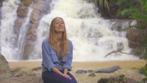 Een jonge vrouw bezoekt de waterval in de bergen. Reis naar Dalat concept — Stockvideo