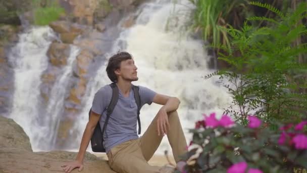 Ein junger Mann besucht einen Wasserfall in den Bergen. Anreise nach Dalat — Stockvideo