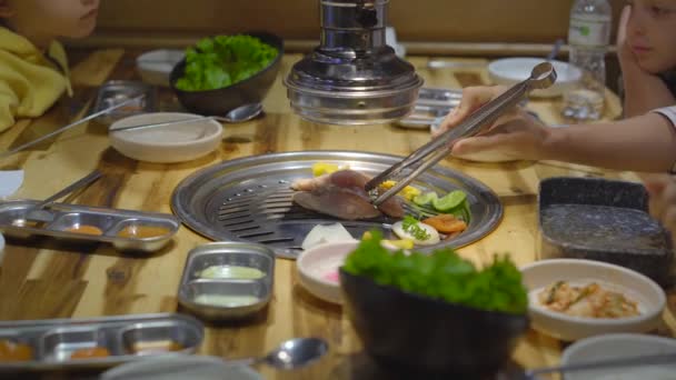 Família visita um restaurante grelhador coreano onde você pode cozinhar sua própria comida. Viagem ao conceito Coreia — Vídeo de Stock