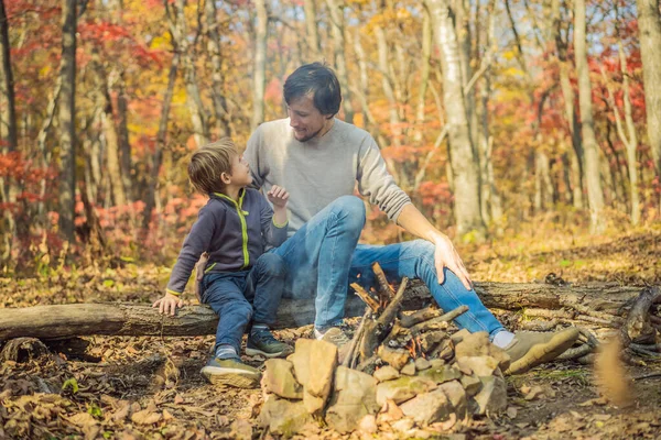 Pai e filho animado sentado na tenda na floresta acampar com fogueira — Fotografia de Stock