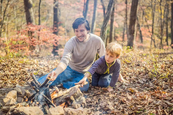 Pai e filho animado sentado na tenda na floresta acampar com fogueira — Fotografia de Stock