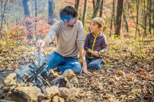 Pai e filho animado sentado na tenda na floresta acampar com fogueira — Fotografia de Stock