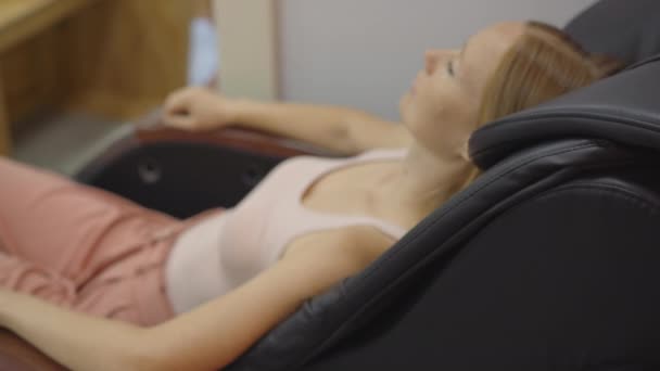 Портативный снимок молодой женщины, сидящей в автоматическом массажном кресле — стоковое видео