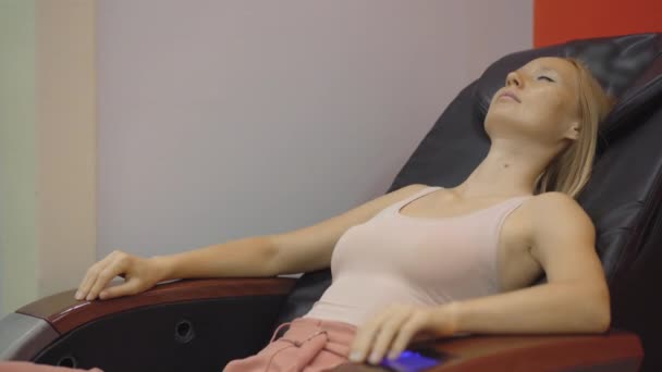 Prise de vue à la main d'une jeune femme assise dans une chaise de massage automatique — Video