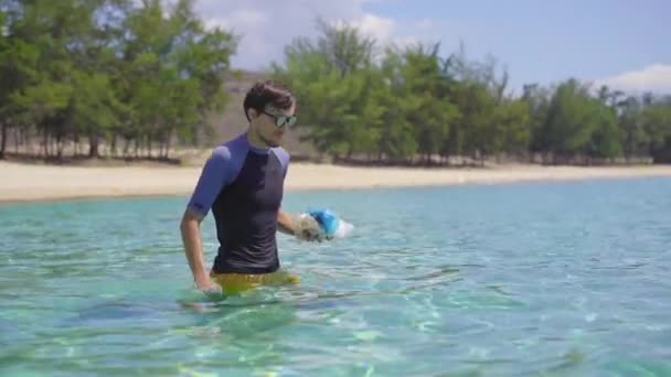 Tiro de mano de un hombre que recoge bolsas de plástico en el hermoso mar turquesa. Paraíso contaminación de la playa. El problema de la basura en la arena de la playa causada por la contaminación causada por el hombre. Eco campañas para — Vídeos de Stock