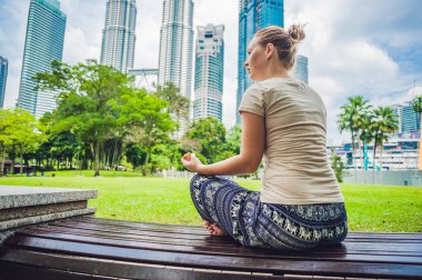 Gökdelenlerin arka planında meditasyon yapan genç bir kadın.