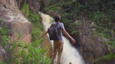 Genç bir adamın yavaş çekimleri dağlardaki şelaleyi ziyaret ediyor. Dalat konseptine yolculuk