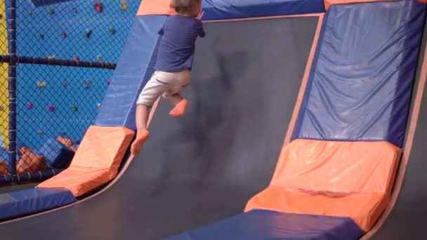 Spowolnione ujęcie małego chłopca w centrum rozrywki trampoliny. — Wideo stockowe