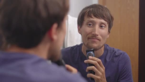 Closeup shot of a young man that shaves his beard using a beard trimmer — Stock Video