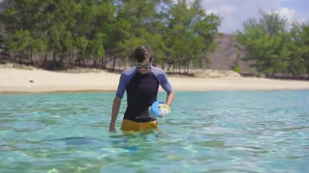 Colpo palmare di un uomo che raccoglie sacchetti di plastica nel bellissimo mare turchese. Paradiso inquinamento spiaggia. Il problema della spazzatura sulla sabbia della spiaggia causata dall'inquinamento causato dall'uomo. Campagne ecologiche — Video Stock