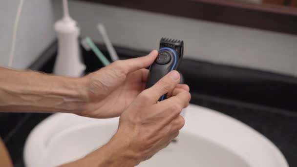 Primo piano di un giovane uomo che si depila la barba con un tagliabarba — Video Stock