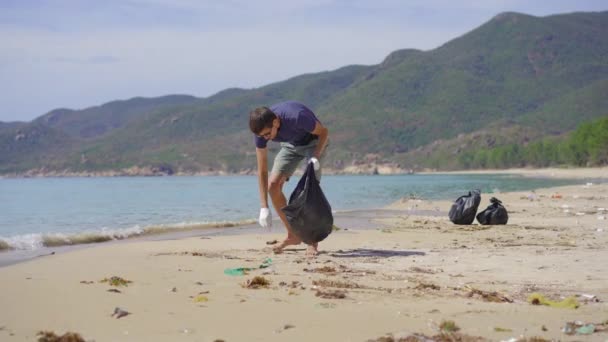 Mann mit Handschuhen sammelt Plastikmüll am Strand ein. Das Problem des Mülls am Strand Sand verursacht durch menschengemachte Verschmutzung. Öko-Kampagnen für saubere Umwelt. Ökologisches Freiwilligenkonzept — Stockvideo