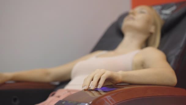 Prise de vue à la main d'une jeune femme assise dans une chaise de massage automatique — Video