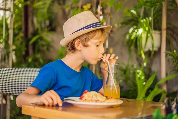 Мальчик ест бельгийские вафли с клубникой в кафе — стоковое фото