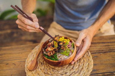 Karides, mısır, avokado, zencefil ve mantarla Poke kasesi yiyen adam.