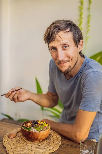 Homem comendo tigela Poke com camarão, milho, abacate, gengibre e cogumelos — Fotografia de Stock