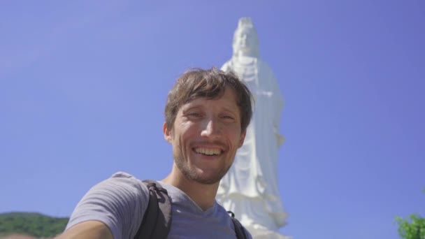 En ung man turist tar selfie video står framför Son Tra Linh Ung Pagoda även känd som Ledy Buddha i staden Da Nang i centrala Vietnam. Resor till Vietnam konceptet — Stockvideo