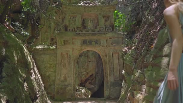 Uma jovem turista visita as montanhas The Marble um complexo de templos budistas, famoso destino turístico na cidade de Da Nang, no centro do Vietnã. Ela atravessa velhos portões para a maior caverna. — Vídeo de Stock