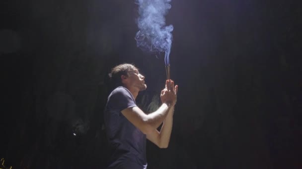 A young european man is praying holding smoking aroma sticks in his hands. He is in the biggest cave temple in the Marble mountains a complex of Buddhist temples, a famous tourist destination in the — Stock Video