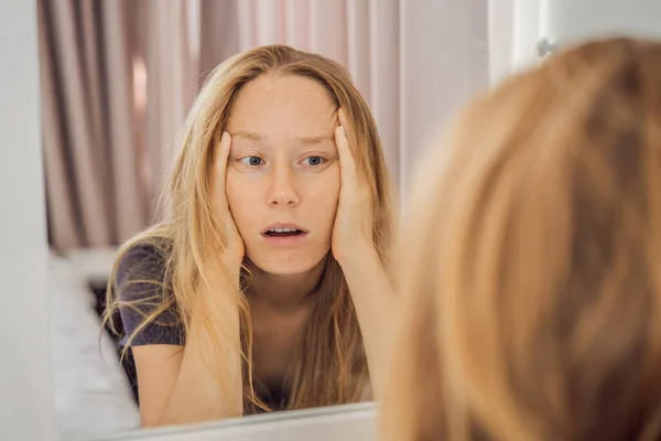 Extremt trött ung kvinna tittar på sig själv i spegeln, ensam hemma. Självisolering hemma, karantän på grund av pandemisk COVID 19. Psykiska hälsoproblem i hemmet vid isolering — Stockfoto