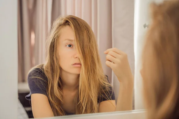 Extremt trött ung kvinna tittar på sig själv i spegeln, ensam hemma. Självisolering hemma, karantän på grund av pandemisk COVID 19. Psykiska hälsoproblem i hemmet vid isolering — Stockfoto