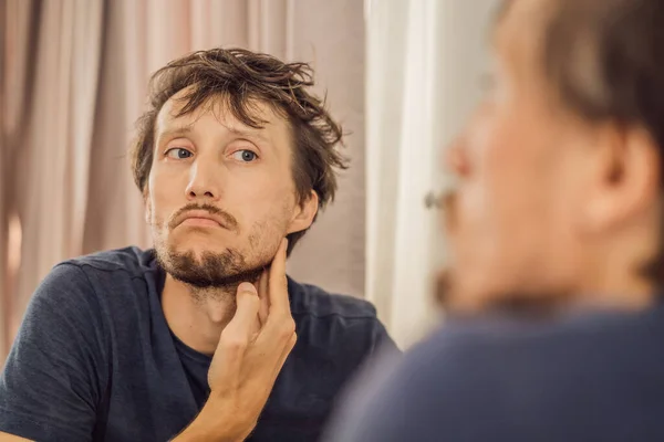 Extremly tired young man looking at himself in the mirror, home alone. self-isolation at home, quarantine due to pandemic COVID 19. Mental health problems in self-isolation at home — Stock Photo, Image