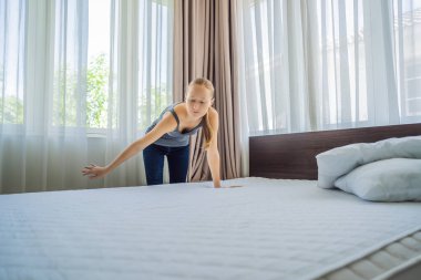 Genç bayan hizmetçi otel odasında yatak değiştiriyor.