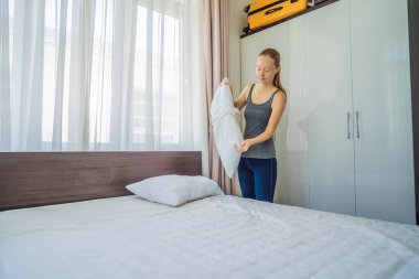 Genç bayan hizmetçi otel odasında yatak değiştiriyor.