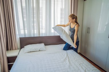 Genç bayan hizmetçi otel odasında yatak değiştiriyor.